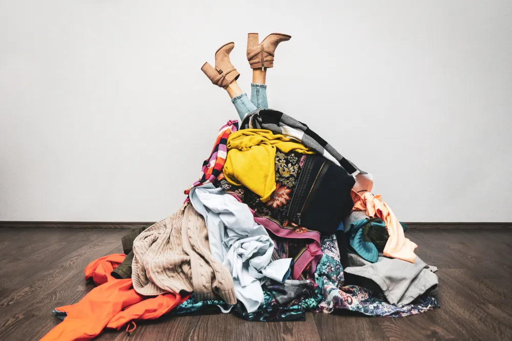 Pile of laundry sitting on ground with white backdrop